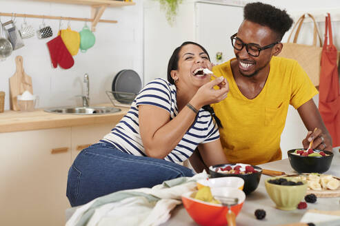 Multiethnisches Paar beim gemeinsamen Frühstück in der Küche - IGGF01407