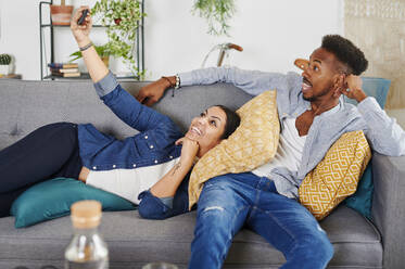 Multiethnic couple spending time together at living room and taking a selfie - IGGF01425