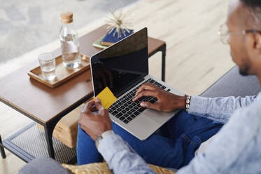 Young man using laptop at living room - IGGF01429