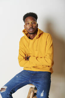 Young man wearing yellow hoodie sweater and glasses - IGGF01435