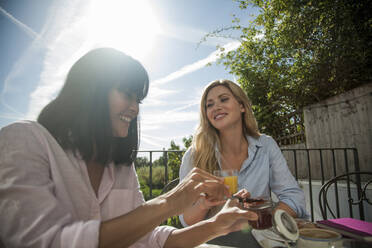 Two women having breakfast at outdoor cafe table, having fun, talking - AJOF00034