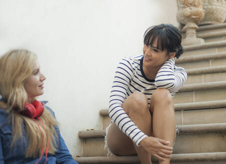 Zwei Frauen unterhalten sich, sitzen auf einer Treppe - AJOF00074
