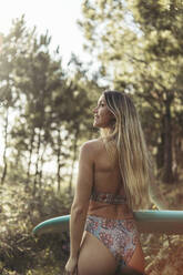 Junge blonde Frau mit einem Surfbrett im Wald - MTBF00093