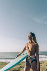 Junge blonde Surferin genießt das Sonnenlicht am Strand von Sopelana, Spanien - MTBF00099