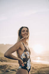 Young blond woman wearing swimsuit at the beach during sunrise - MTBF00108