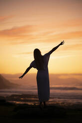 Silhouette einer jungen Frau bei Sonnenaufgang am Strand - MTBF00126