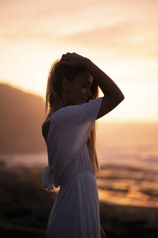 Young woman at the beach during sunrise stock photo