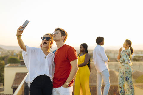 Junge Frau und Mann machen ein Selfie während einer Party am Abend, lizenzfreies Stockfoto