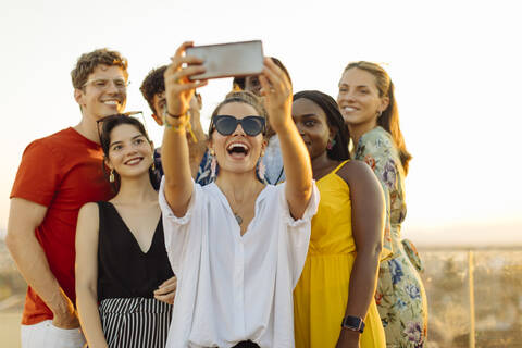 Gruppe fröhlicher multiethnischer Freunde, die während einer Party am Abend ein Selfie machen, lizenzfreies Stockfoto