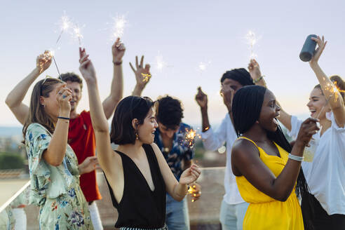 Gruppe fröhlicher multiethnischer Freunde, die abends eine Party feiern, mit Wunderkerzen in der Hand - SODF00185