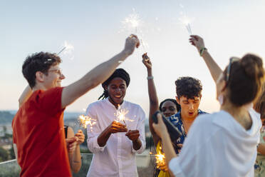 Gruppe fröhlicher multiethnischer Freunde, die abends eine Party feiern, mit Wunderkerzen in der Hand - SODF00187