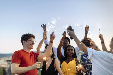 Group of happy multi-ethnic friends celebrating a party in the evening, holding sparklers - SODF00188