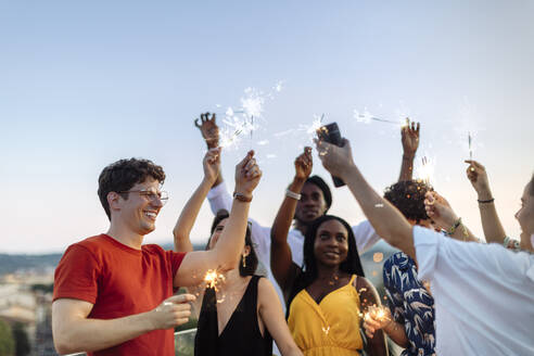 Gruppe fröhlicher multiethnischer Freunde, die abends eine Party feiern, mit Wunderkerzen in der Hand - SODF00188