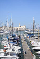 Italy, Apulia, Trani, Boats moored in marina with San Nicola Pellegrino cathedral in background - HLF01199
