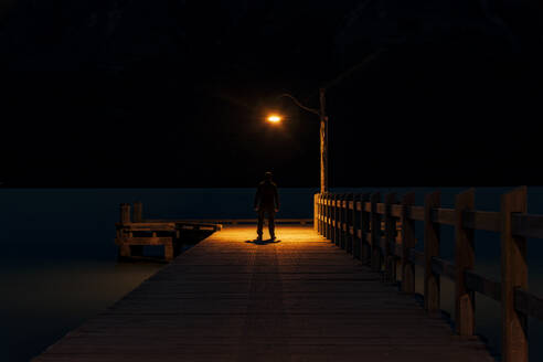 Rear view of a man standing on pier at night - SMAF01659