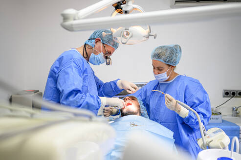 Zahnchirurg und Assistentin arbeiten beim Setzen von Zahnimplantaten - OCMF00874