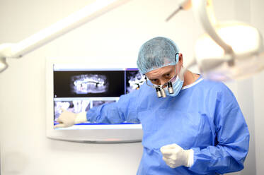 Zahnarzt und Chirurg zeigen dem Patienten eine Röntgenaufnahme des Implantats - OCMF00875