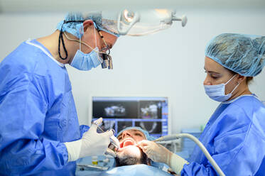 Dental surgeon and assistant work putting dental implant - OCMF00877