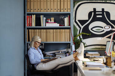 Mature woman working in architct's office, with feet up - SODF00212