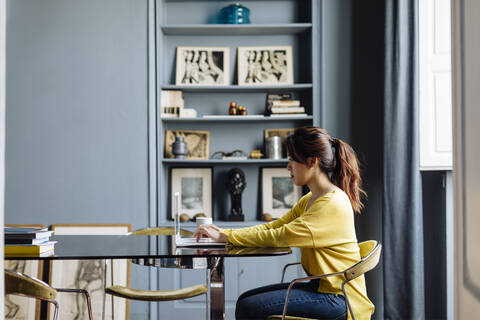Junge Frau mit Laptop in einem Designbüro, lizenzfreies Stockfoto