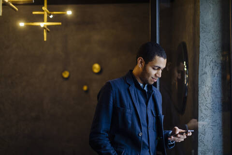 Junger Mann in einem stilvollen Büro, der ein Smartphone benutzt, lizenzfreies Stockfoto