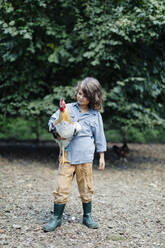 Junge hält Huhn auf einem Bio-Bauernhof - SODF00311