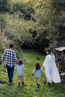 Rückansicht einer Familie mit zwei Kindern bei einem Spaziergang auf dem Lande - SODF00318