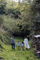 Rückansicht einer Familie mit zwei Kindern bei einem Spaziergang auf dem Lande - SODF00319