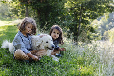 Two kids relaxing with dog on a meadow - SODF00337