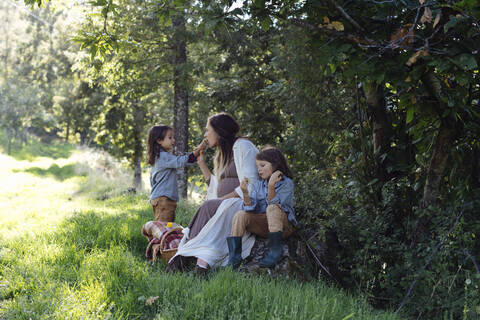 Schwangere Mutter mit zwei Kindern beim Picknick auf dem Lande, lizenzfreies Stockfoto