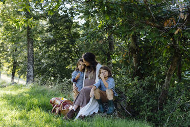 Pregnant mother with two kids having a picnic in the countryside - SODF00339