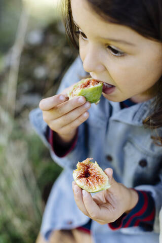 Kind isst eine Feige im Freien, lizenzfreies Stockfoto