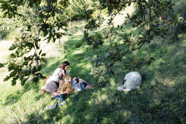 Mutter mit zwei Kindern und Hund beim Entspannen auf dem Lande - SODF00351