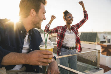 Happy young couple having a rooftop party at sunset - UUF19451