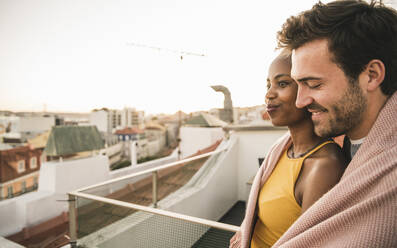 Portrait of affectionate young couple on rooftop in the evening - UUF19495