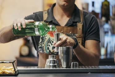 Barkeeper beim Mixen eines Cocktails in einer Bar, mit Jigger - MTBF00142