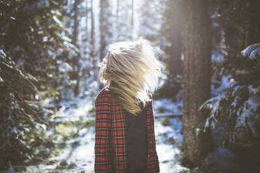 Frau schüttelt den Kopf, während sie im Winter im Wald steht - CAVF68278