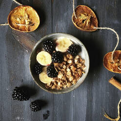 Draufsicht auf Müsli mit Früchten in einer Schale mit Girlande auf einem Holztisch - CAVF68318