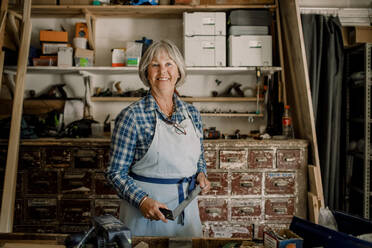 Porträt einer selbstbewussten älteren Unternehmerin, die in einem Workshop ein Quadrat hält - MASF14022