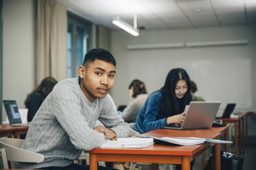 Porträt Jugendlicher am Schreibtisch sitzend im Klassenzimmer - MASF14086