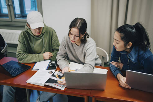 Blick von oben auf Studenten, die mit einem Laptop am Schreibtisch in der Schule sitzen und lernen - MASF14097