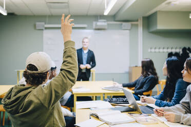 Jugendlicher mit erhobener Hand während des Unterrichts im Klassenzimmer - MASF14117