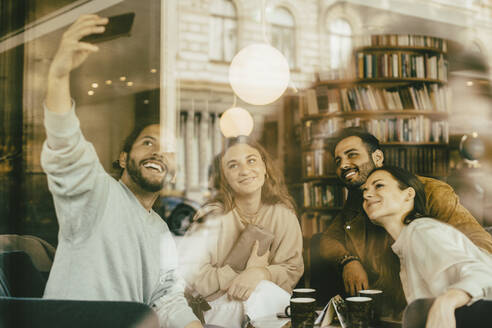 Freunde, die ein Selfie machen, während sie im Restaurant sitzen, gesehen durch Glas - MASF14147