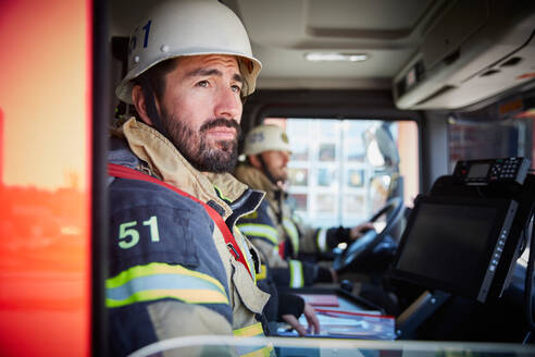 Feuerwehrmann schaut durch ein Fenster, während er im Feuerwehrauto sitzt - MASF14165