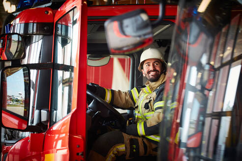 Feuerwehrmann schaut weg, während er im Feuerwehrauto auf der Feuerwache sitzt - MASF14182