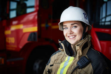 Porträt einer lächelnden Feuerwehrfrau mit Helm auf der Feuerwache - MASF14186