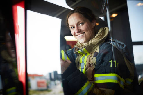 Porträt einer lächelnden Feuerwehrfrau, die in einem Feuerwehrauto sitzt - MASF14189