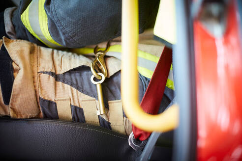 Mittelteil eines Feuerwehrmanns mit Schlüsselanhänger im Feuerwehrauto sitzend - MASF14196
