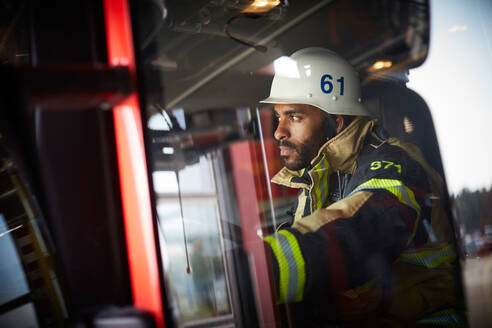 Selbstbewusster Feuerwehrmann, der im Feuerwehrauto sitzt und wegschaut - MASF14203