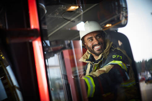 Lächelnder Feuerwehrmann im Feuerwehrauto durch ein Glasfenster gesehen - MASF14204